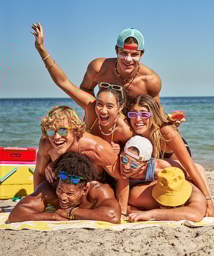 Chubbies swimwear editorial image of seven people posing and smiling for the camera at the beach